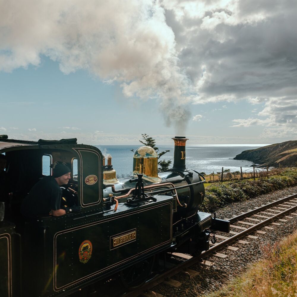Victorian steam train on the rail overlooking the sea.