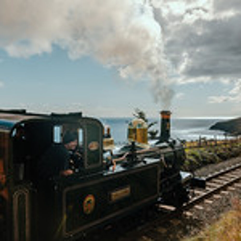 Victorian steam train on the rail overlooking the sea.