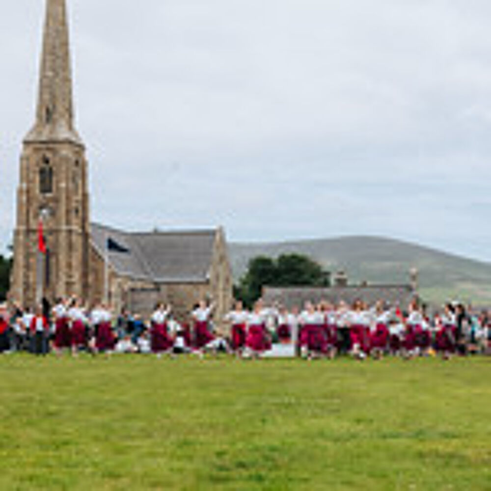People gathered outside a church, dressed in traditional clothing for Tynwald day.