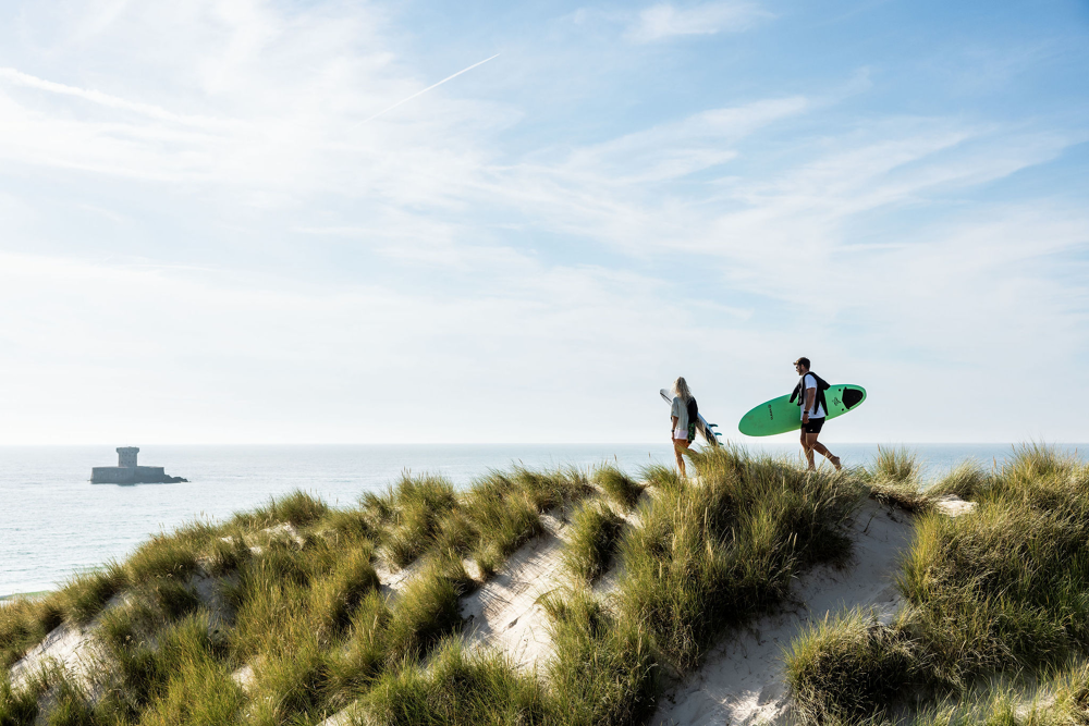 Surfers walking on the sand dunes at St Ouen's Bay.